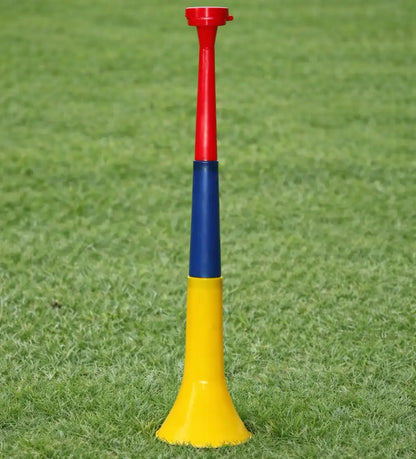 Silbato deportivo rojo, azul y amarillo sobre césped verde
